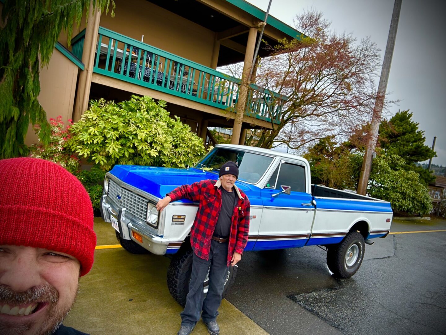 A man standing next to a blue and white truck.